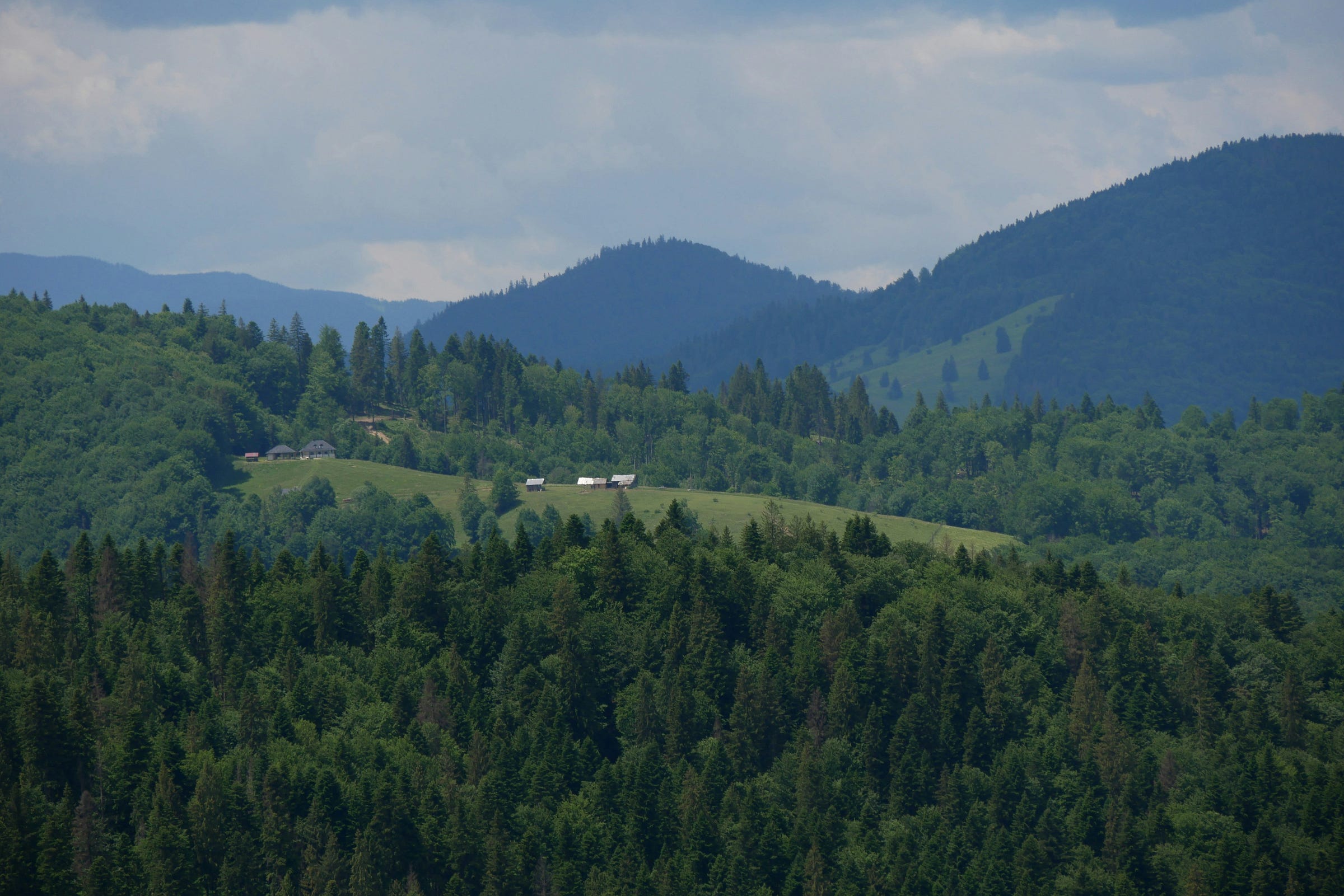 Bucovina, Romania - Photo by Octavian. Depictes traditional homes off in the distance, mountains surround them. Bucovina, Romania - Photo by Octavian. Depictes traditional homes off in the distance, mountains surround them.