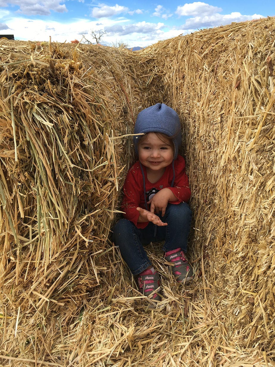 Little girl hiding in between hay bales.
