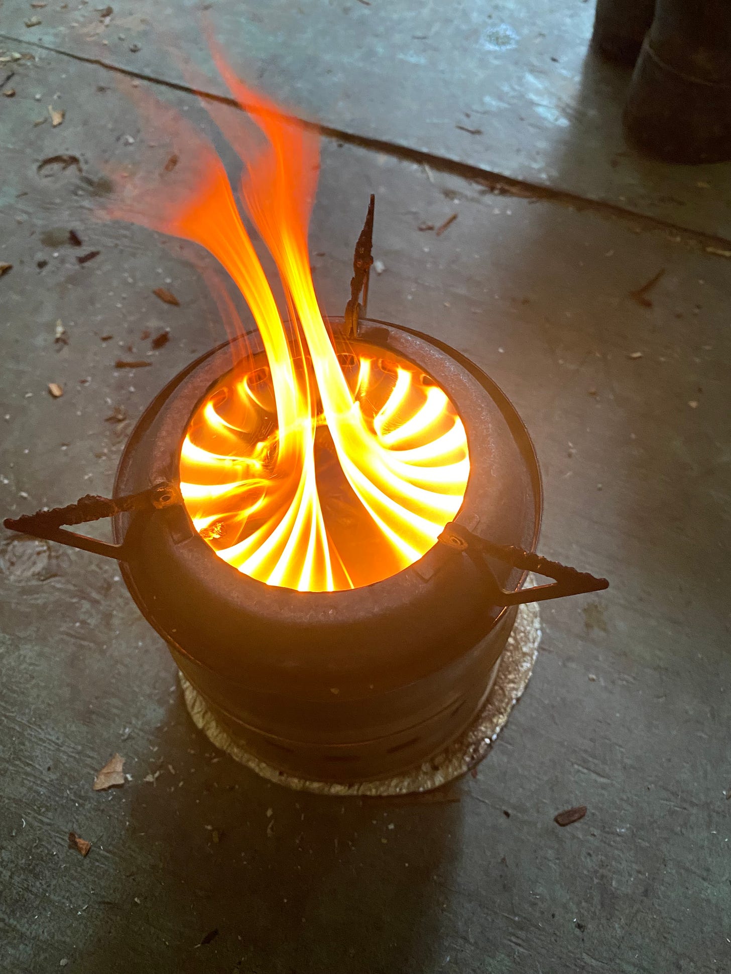 A small, can-style campstove with flame flowing up from it