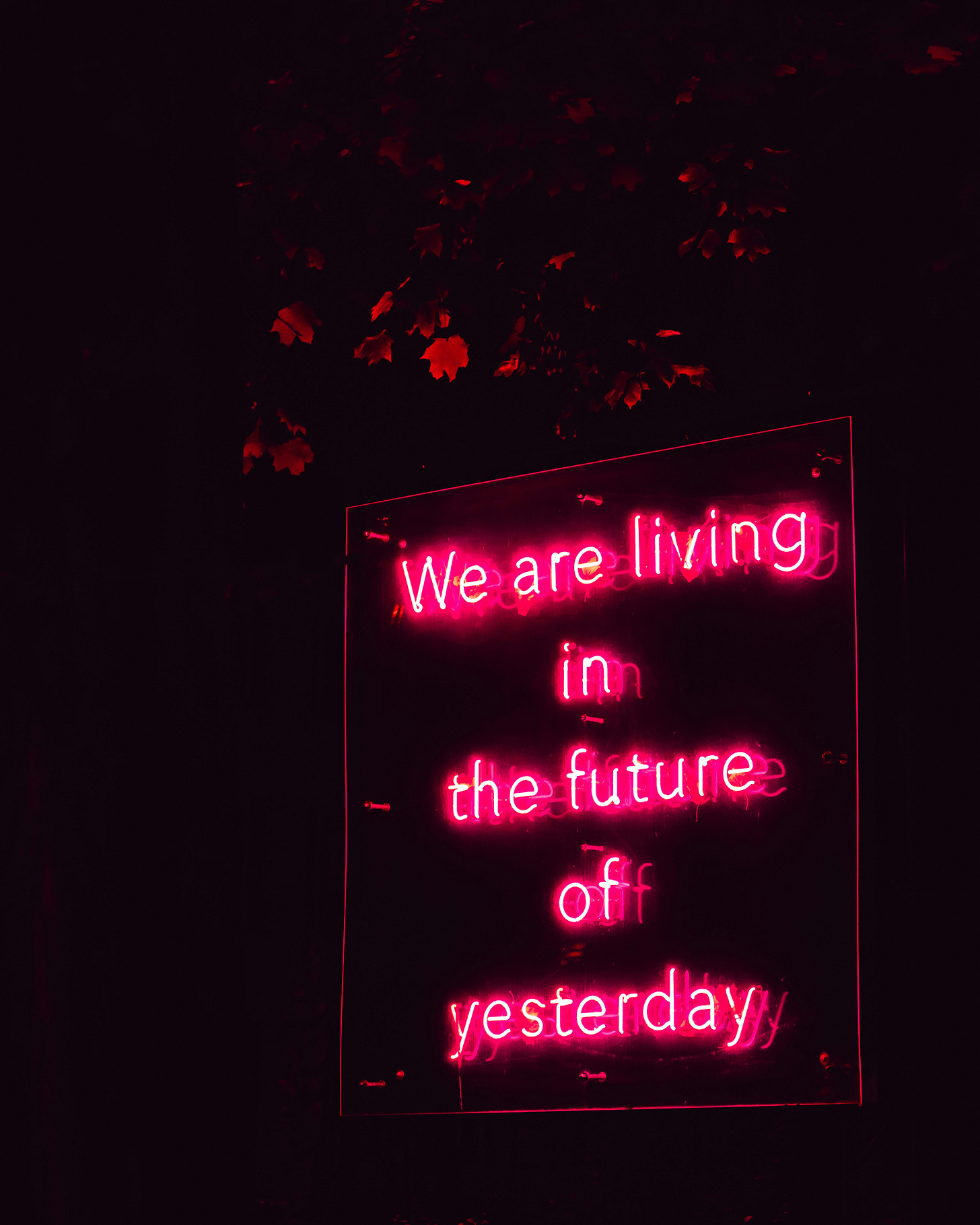 Pink neon sign which reads: we are living in the future of yesterday