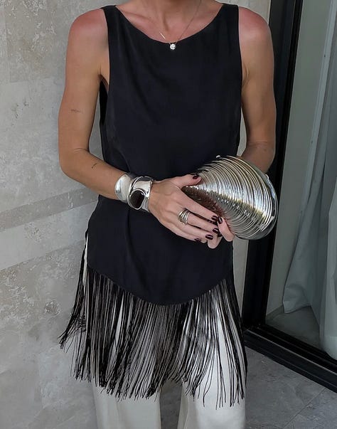 model in blue skirt, graphic t-shirt, black fringed top