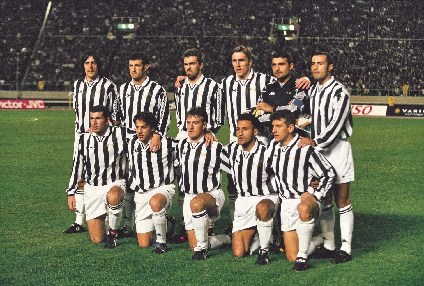 Juventus players line up for a team photo in black-and-white striped kits before a nighttime match, 1990s era.