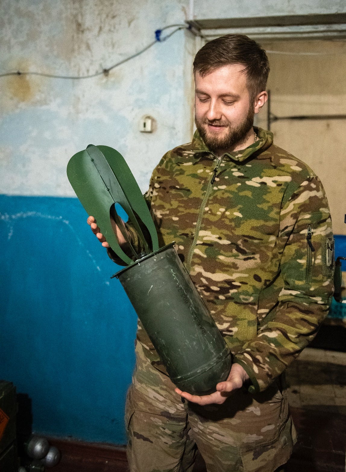 A person in camouflage holding a green metal cylinder

AI-generated content may be incorrect.