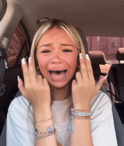 a woman sitting in a car with her mouth open making a face