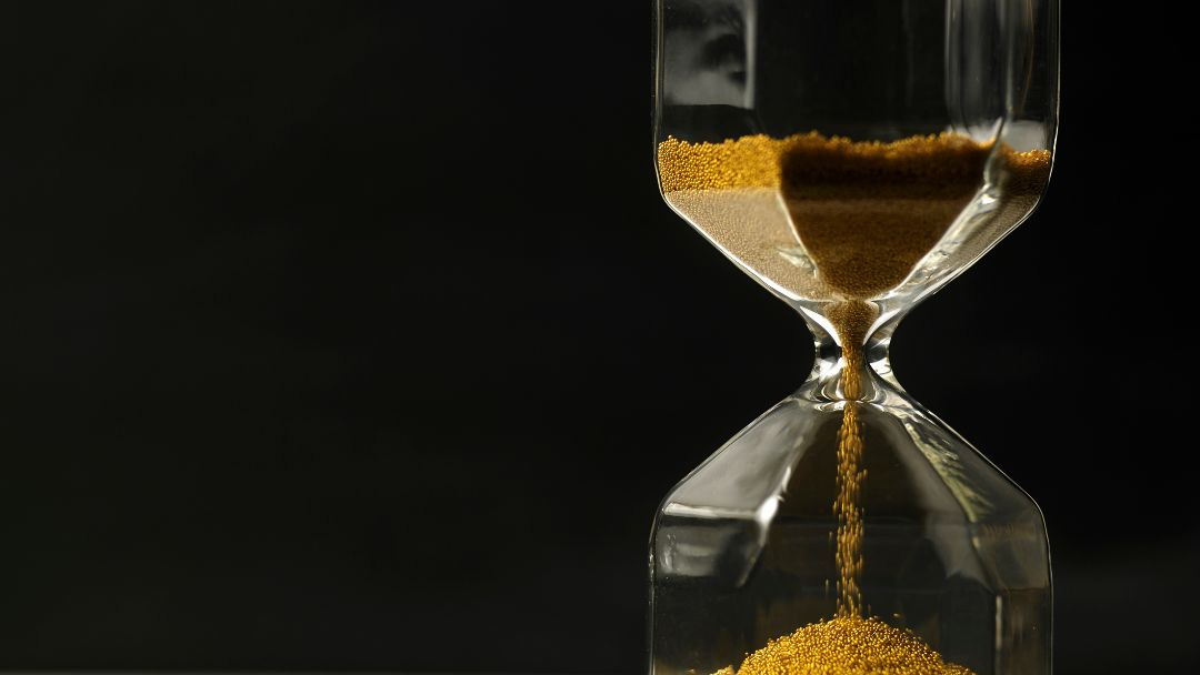 An hourglass with goldish-brown sand against a black background, symbolizing the passage of time and the importance of focus and balance.