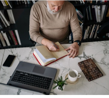 A person sitting at a desk writing in a book

AI-generated content may be incorrect.