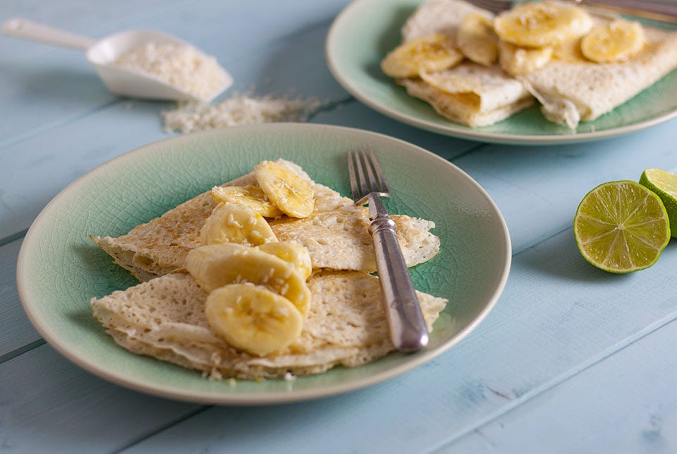 gluten free coconut pancakes on a plate topped with banana and coconut.