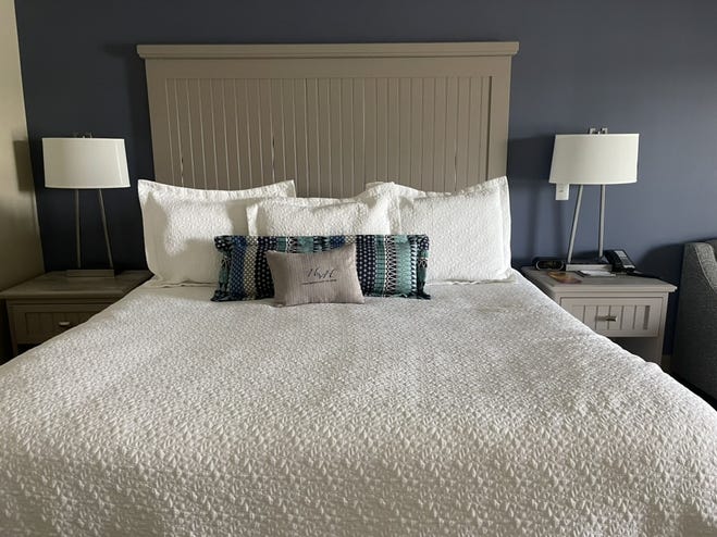 A neatly made bed featuring a simple beige headboard and crisp white bedding. 