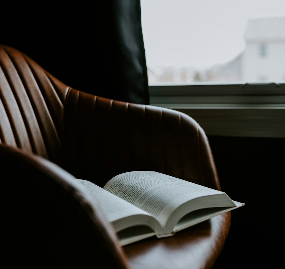 an open book sitting on top of a brown chair
