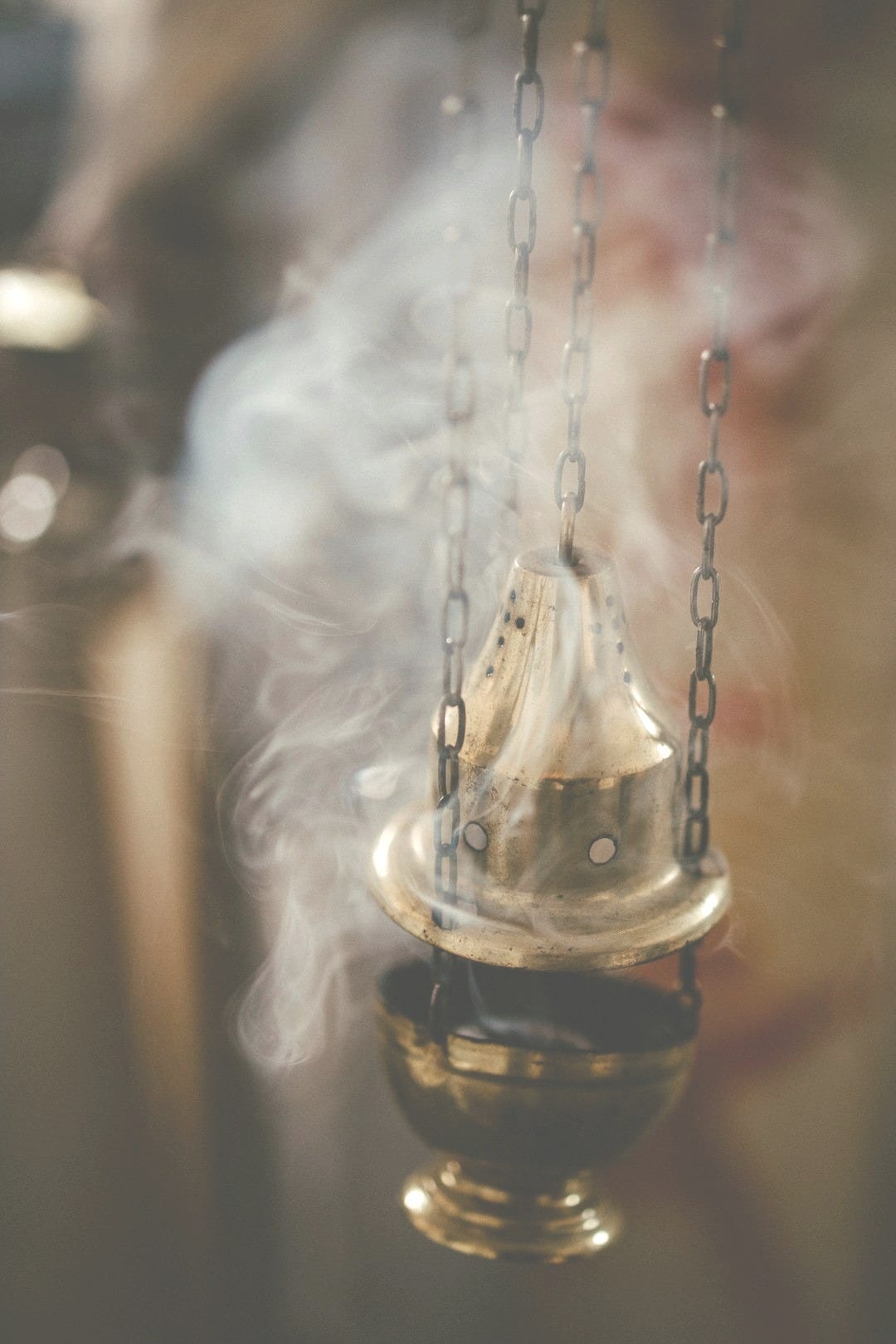 a small bell hanging from a chain with smoke coming out of it