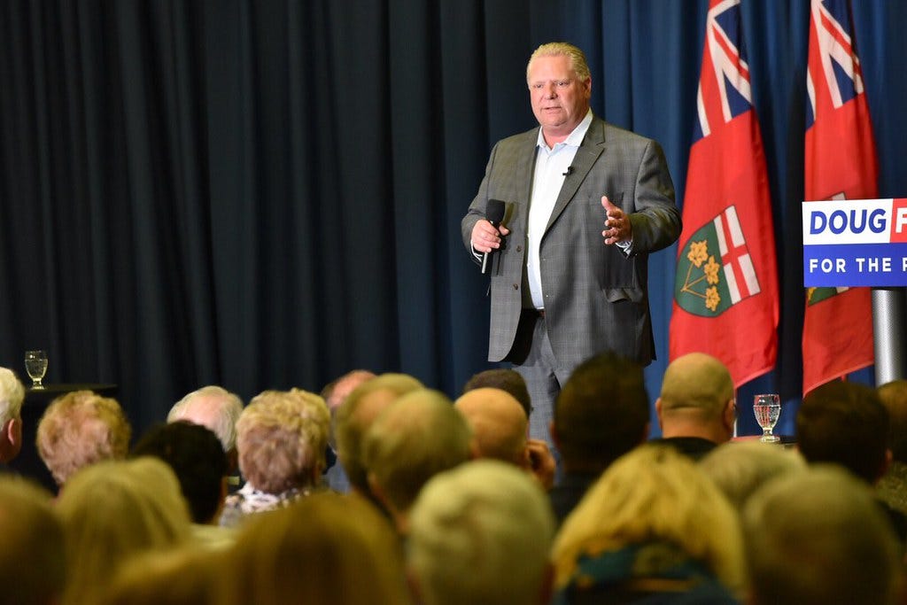 Ontario premier doug ford speaks to a crowd standing ahead of a podium that reads his name and "for the people" Ontario premier doug ford speaks to a crowd standing ahead of a podium that reads his name and "for the people"
