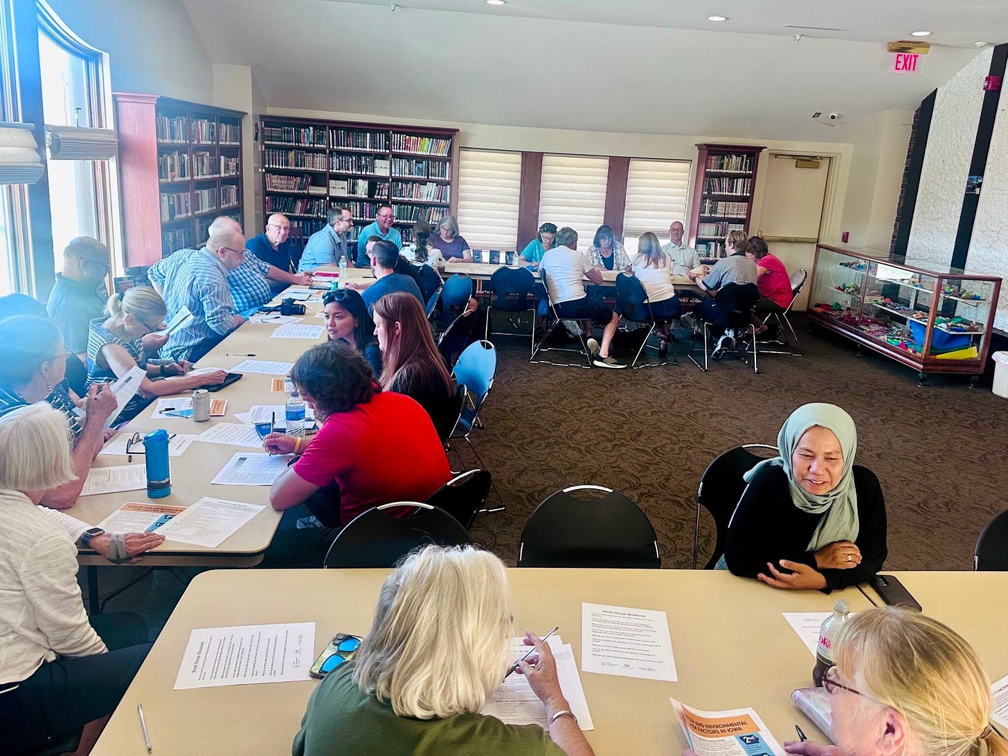 A room with people sitting at various tables A room with people sitting at various tables