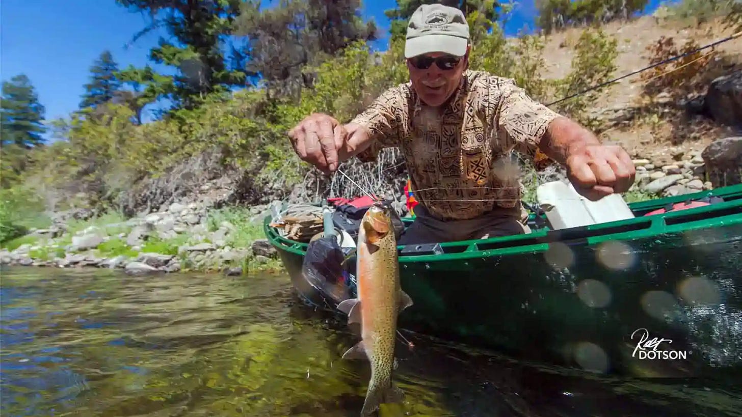 Angler leaning over side of Drift Boat with Cutthroat