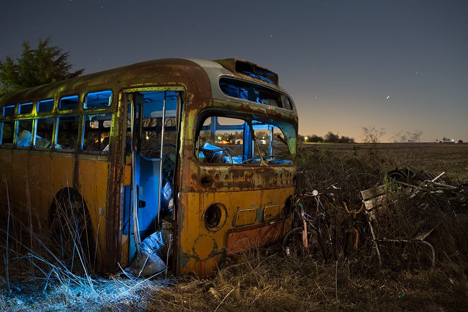 An abandoned 1948 General Motors “Old Look” coach bus at night with blue flashlight illuminating the inside