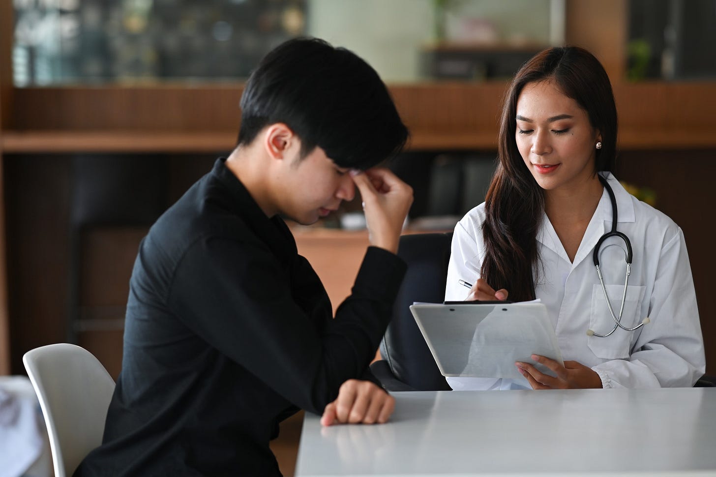 Unhappy depressed young man consulting his health problem with female professional psychiatris.