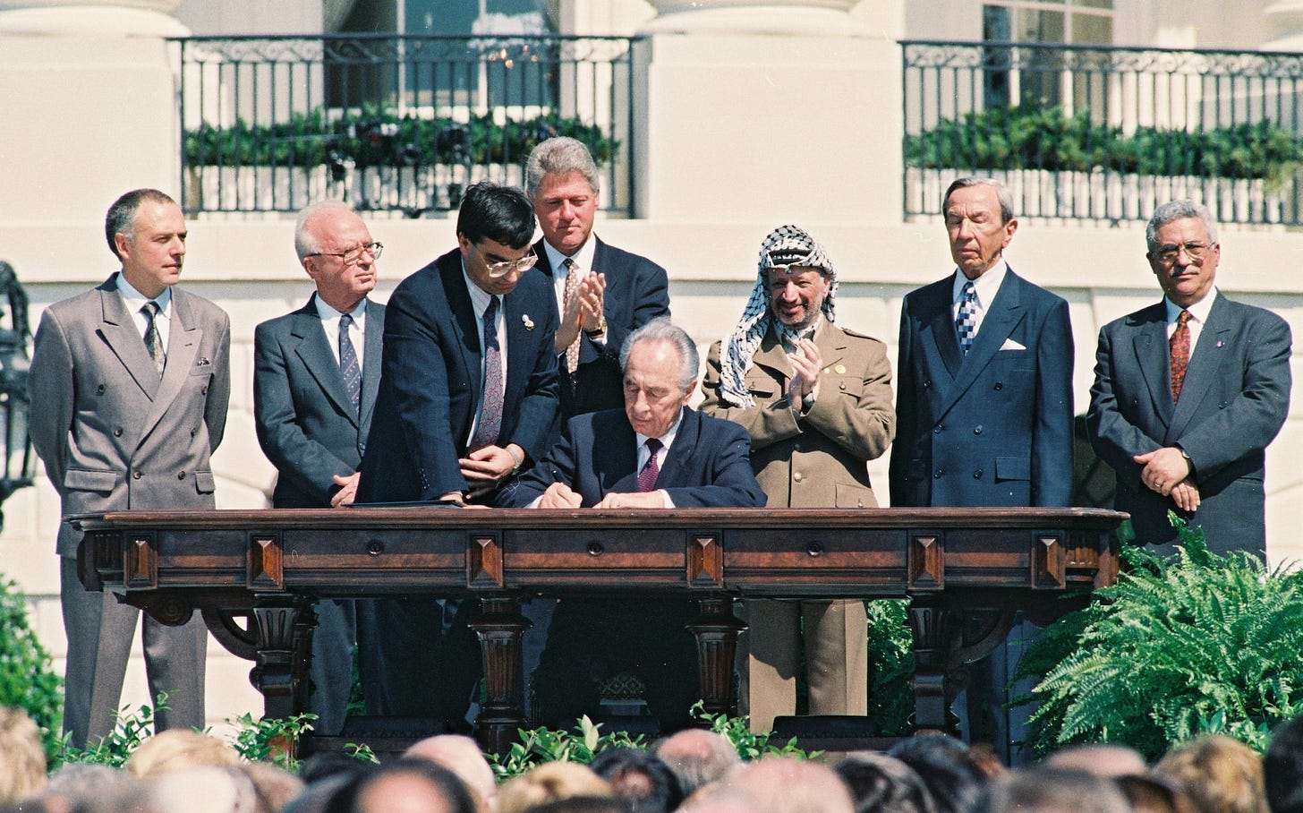 Israeli Foreign Minister Shimon Peres signs the Oslo Accords on the White House Lawn. Behind him are U.S. President Bill Clinton, PLO Chairman Yasser Arafat, Israeli Prime Minister Yitzhak Rabin, Palestinian Prime Minister Mahmoud Abbas and other world leaders, Washington DC, September 13, 1994. (Avi Ohayon/GPO)