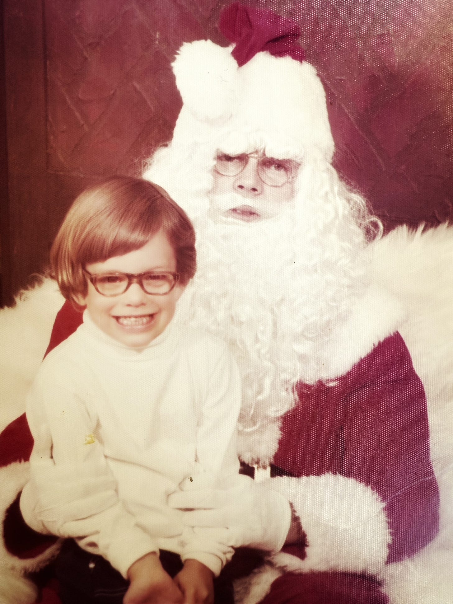 Four year-old boy (me) sits awkwardly on the lap of a stranger dressed in a poorly constructed Santa costume. 