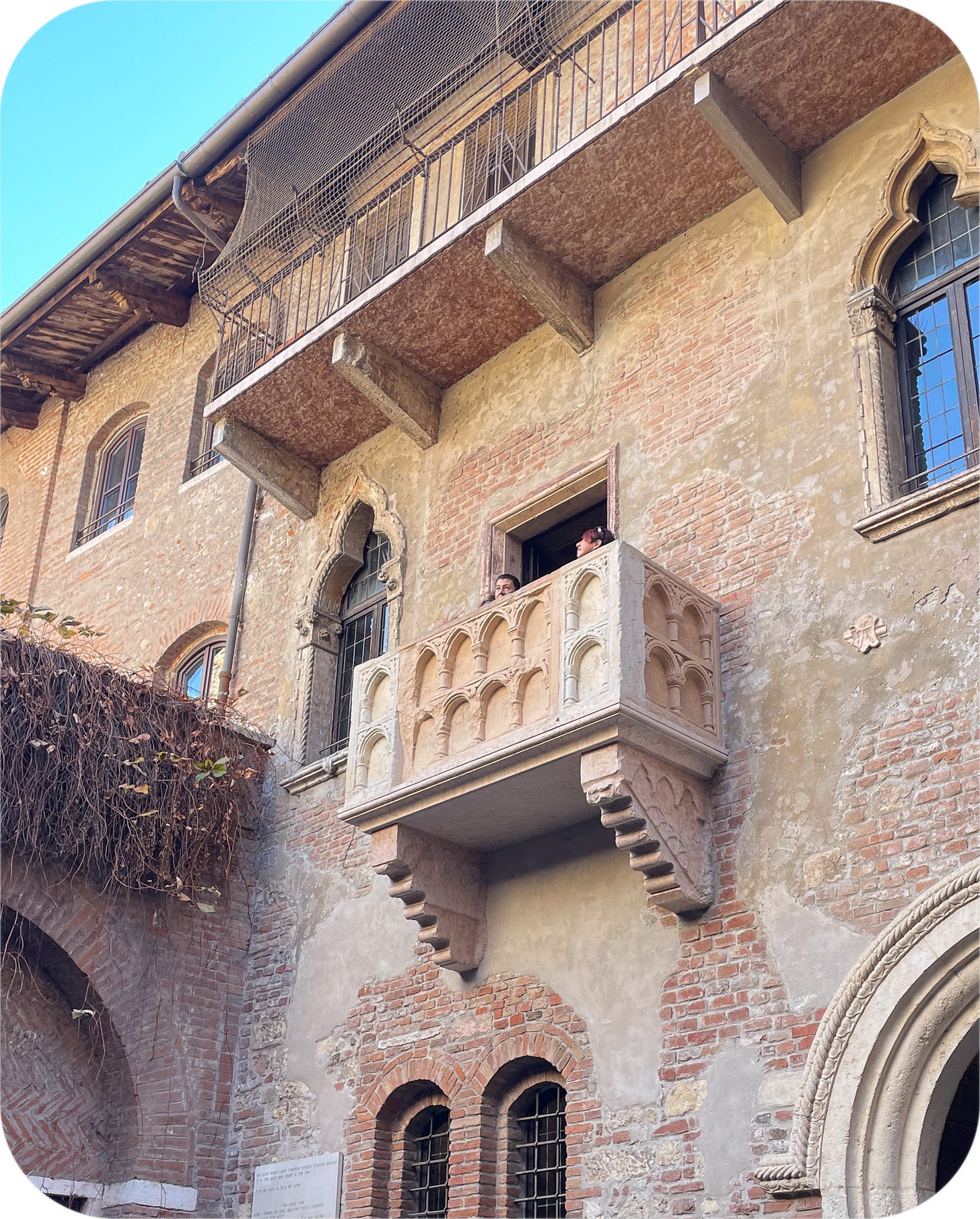 Tourists peek over Juliet's balcony. Verona, Italy.
