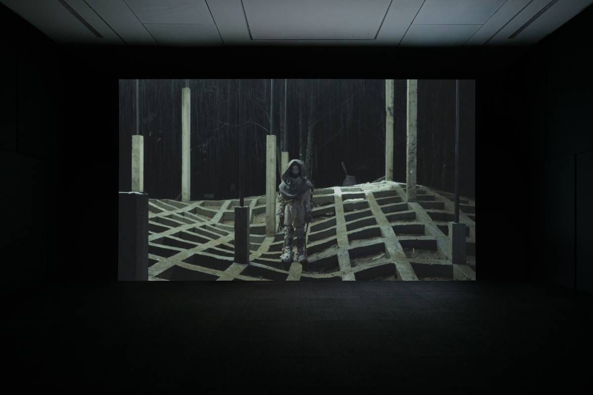 An installation image of a video work playing in a dark room. An installation image of a video work playing in a dark room.