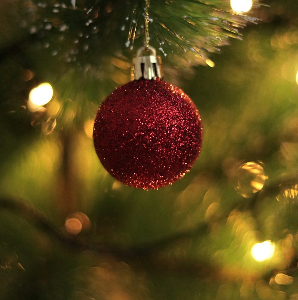 a red ornament hanging from a christmas tree