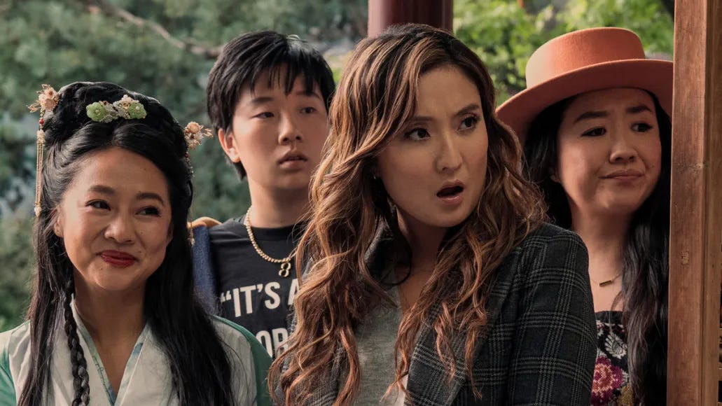 Four Asian women stand looking off camera with varying facial expressions, ranging from pleased to surprised.