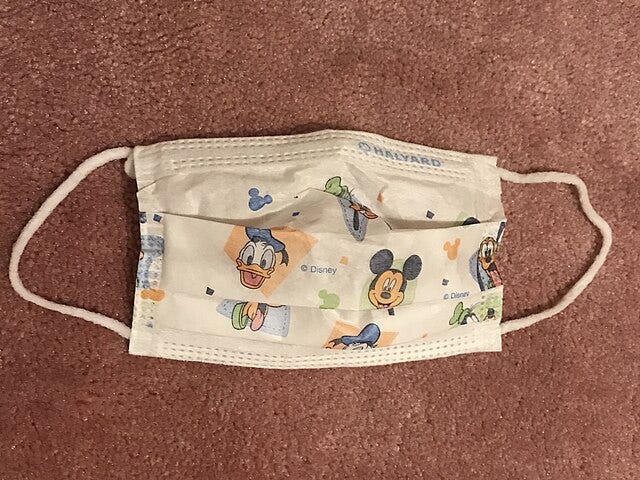 A face mask designed for children, with images of Donald Duck and Mickey Mouse.