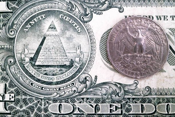One Dollar Bill and a quarter Close-up on a 1 dollar bill with the focus on the Eye Of Providence and on the eagle of 25 cents coin. close-up-of-great-seal-of-the-united-states-on-dollar-bill stock pictures, royalty-free photos & images