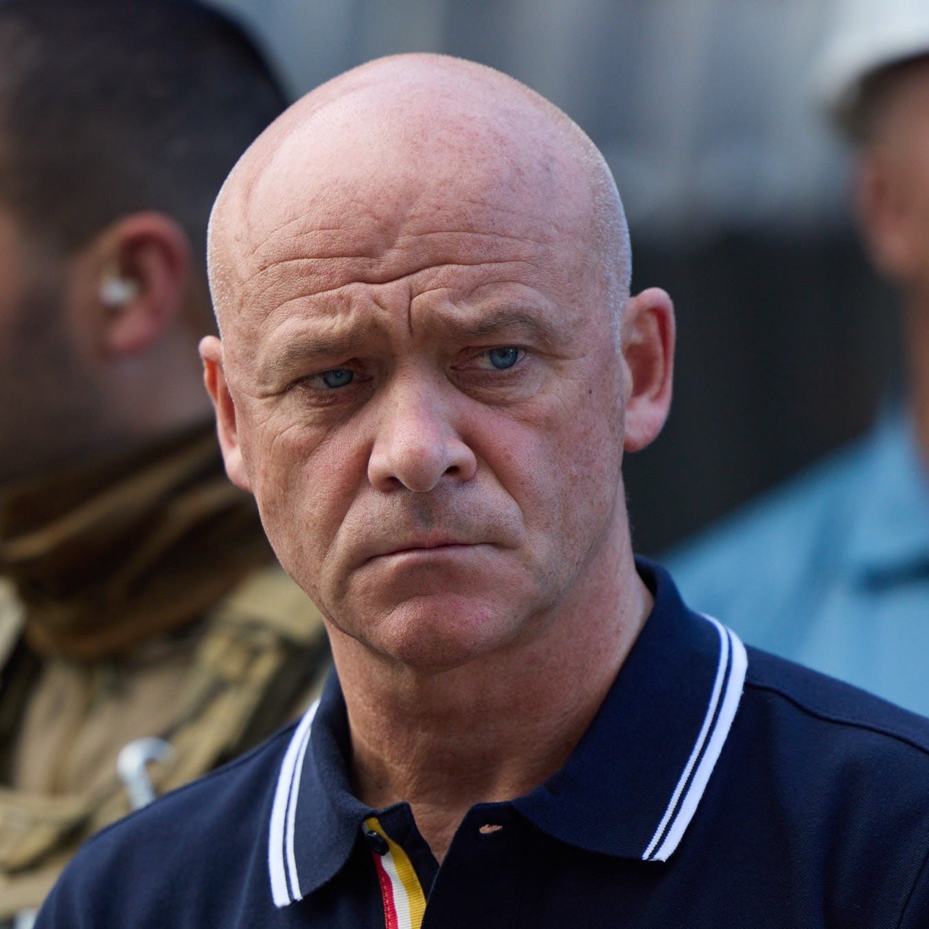 A bald, middle-aged man, Gennadiy Trukhanov, is photographed in 2022. He wears a somber expression and a T-shirt with Odesa's emblem on it.