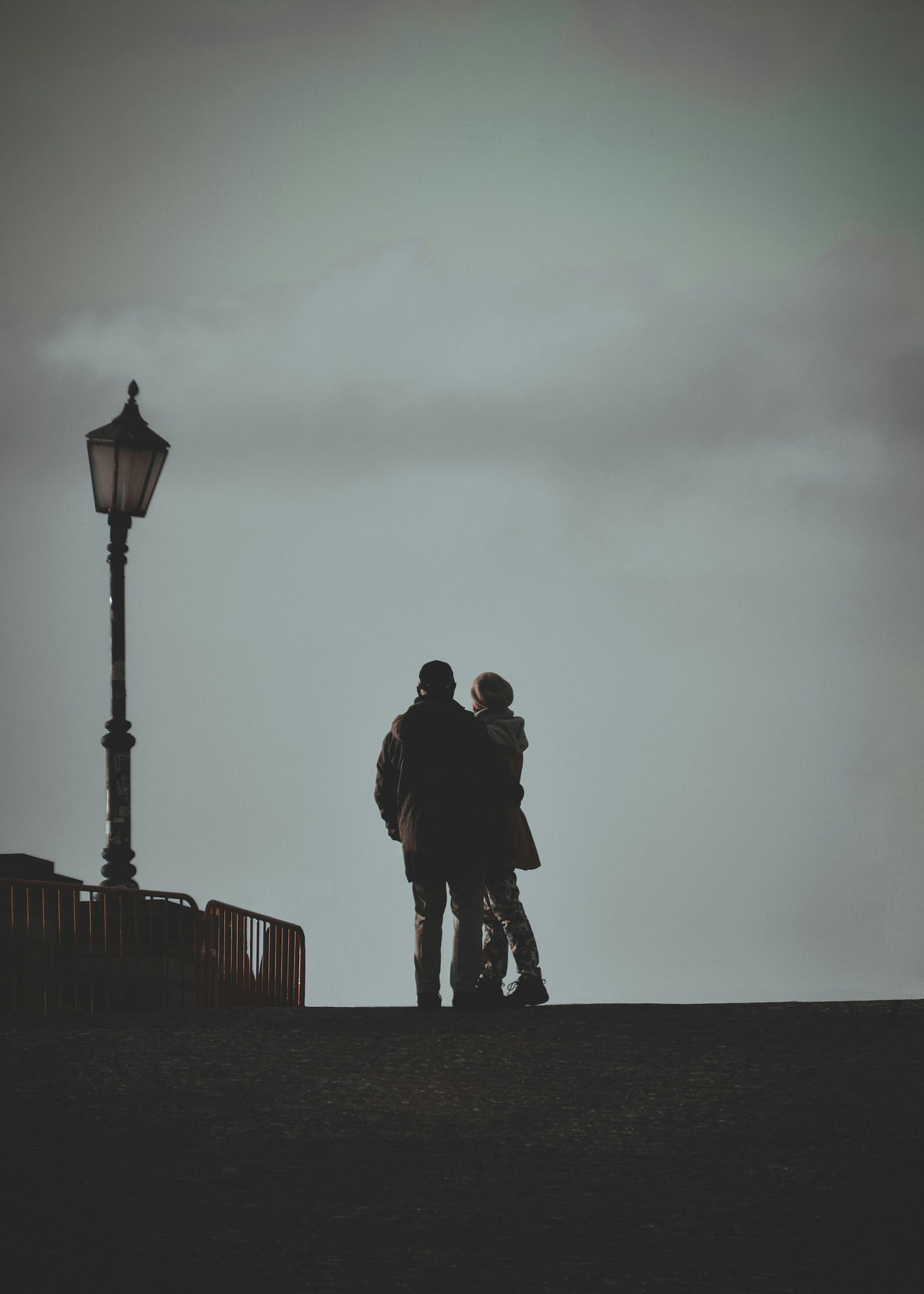 two people standing next to each other near a street light two people standing next to each other near a street light