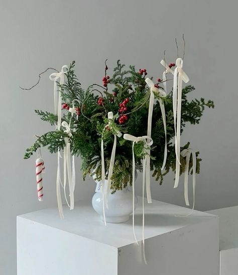This may contain: a white vase filled with greenery and candy canes on top of a table