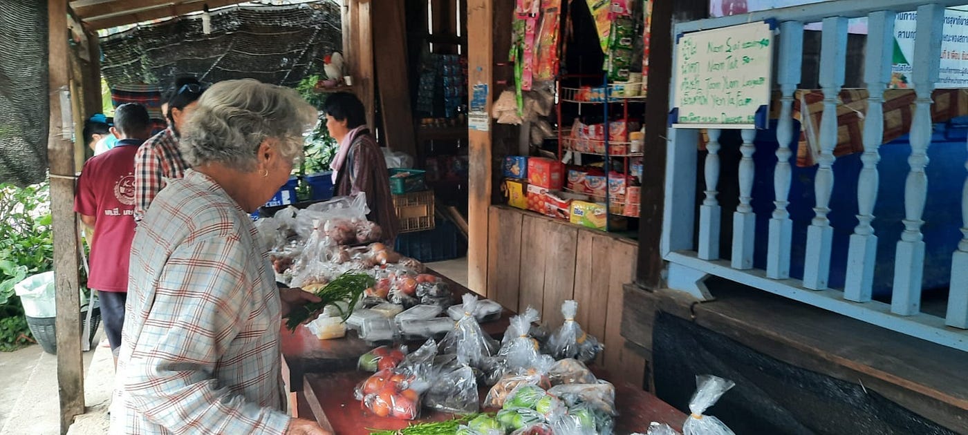 A villager buying goods in a village shop. Many are made and packed by the shop owner.
