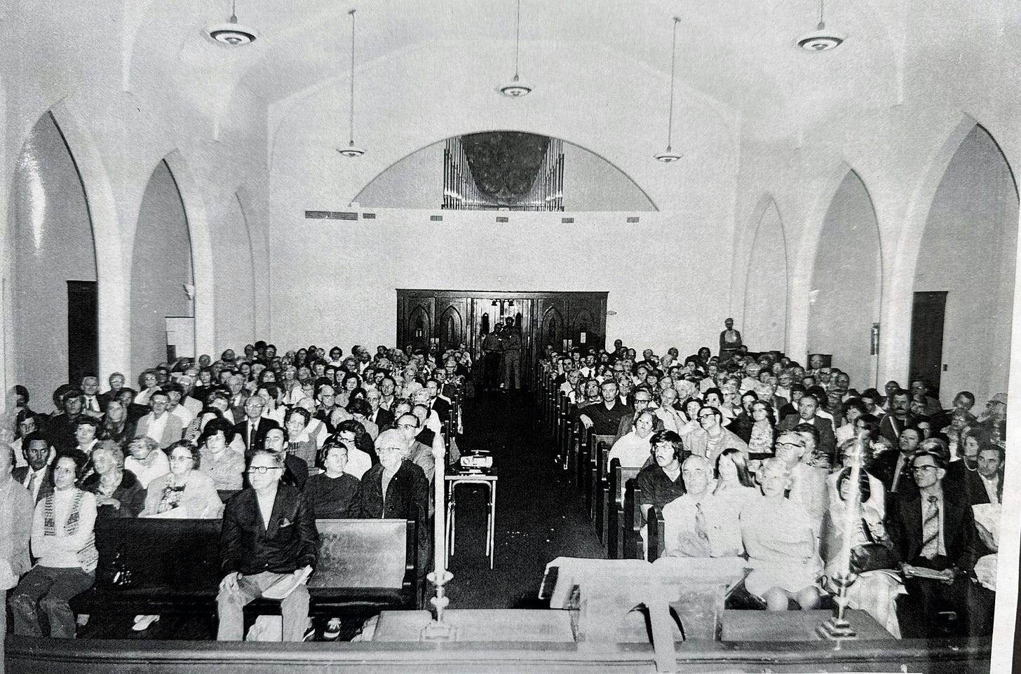 Black and white photo, taken from the pulpit, of a church service with crowded sanctuary. Black and white photo, taken from the pulpit, of a church service with crowded sanctuary.