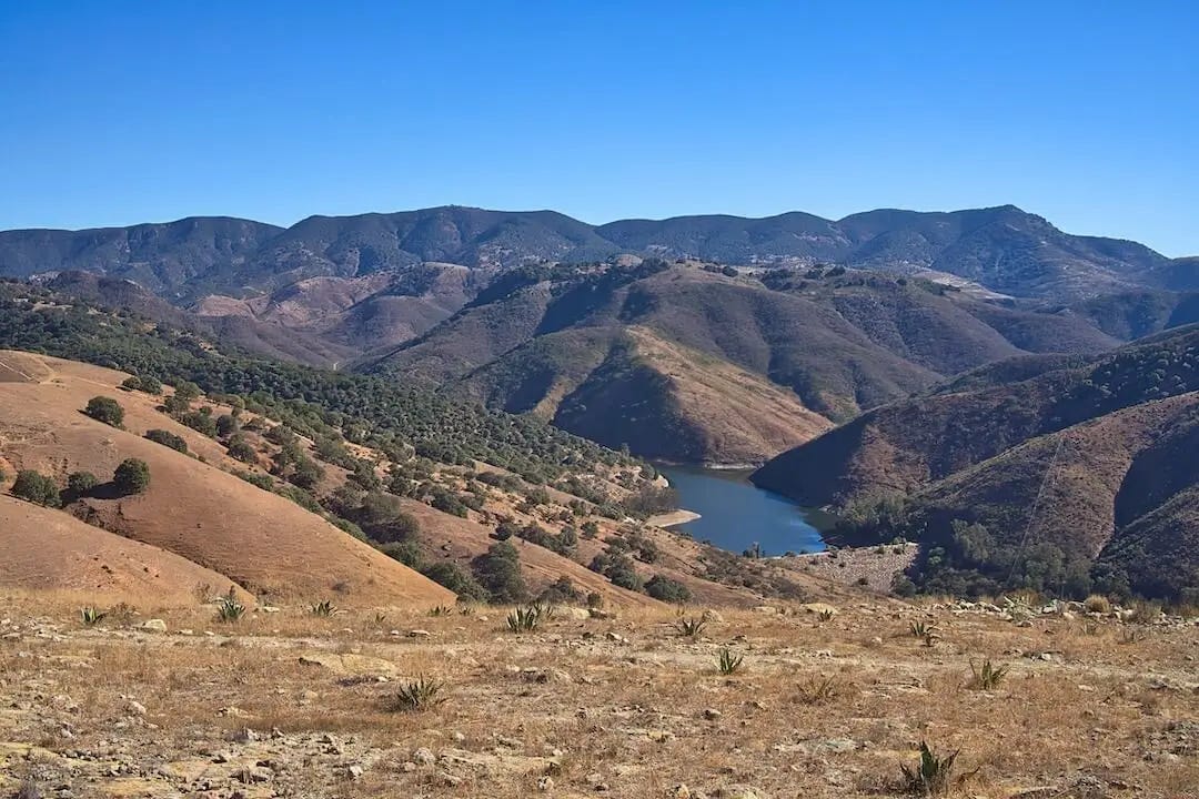 Barren mountains in the background with a blue lake in the foreground