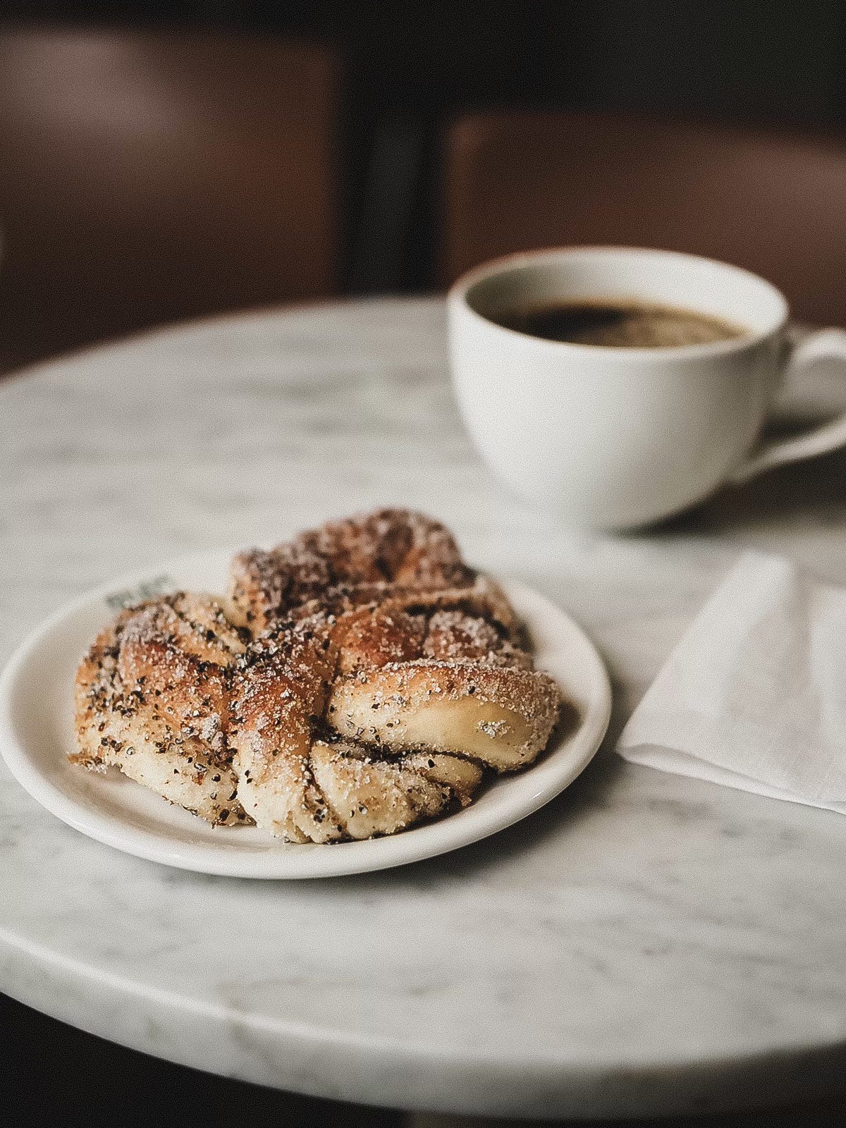 Close-up of a cardamom bun and coffee cup on a marble table