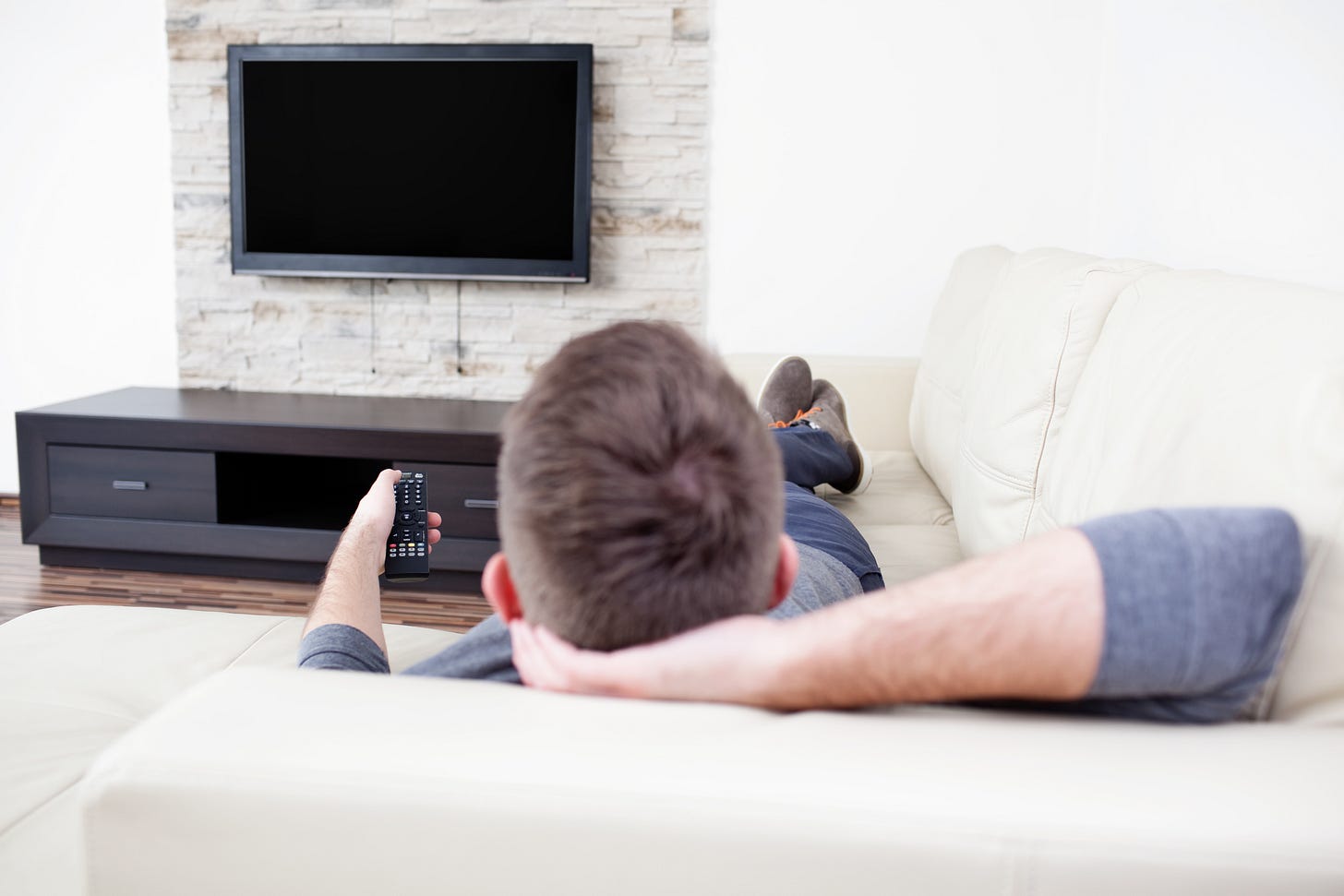 Man reclining on a couch getting ready to watch TV Man reclining on a couch getting ready to watch TV