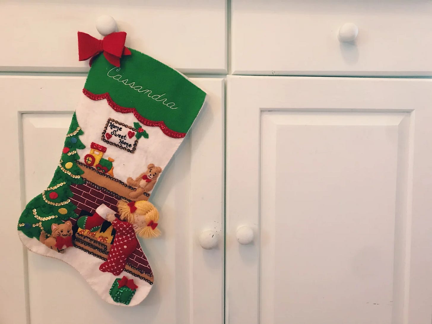 A felt stocking with a girl in front of a fire place and Christmas tree. The name Cassandra is embroidered on top.