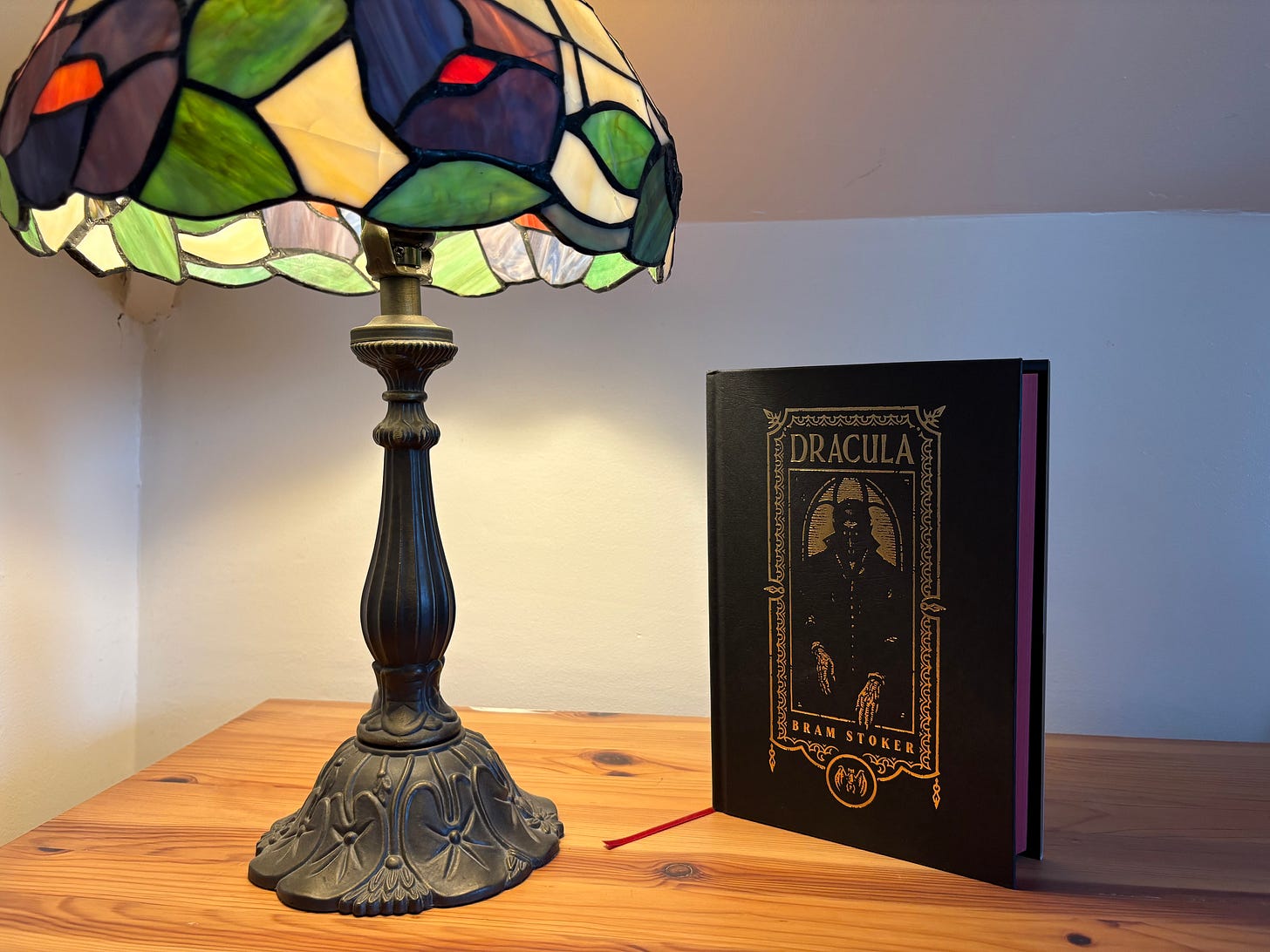 Lamp on a dresser in corner of house with bram stoker's dracula novel partially shadowed in its light