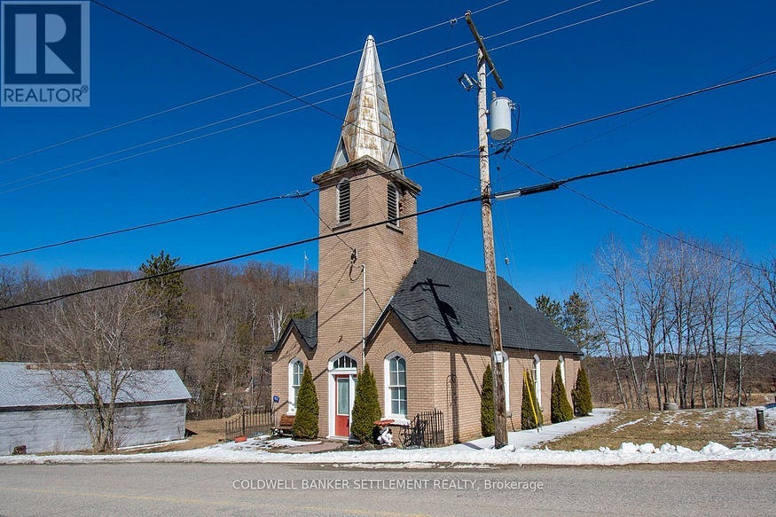 A small former church sits by a road in winter, against blue skies. A small former church sits by a road in winter, against blue skies.