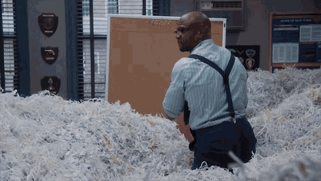 a man is standing in a pile of shredded paper in front of a bulletin board that says news of new york