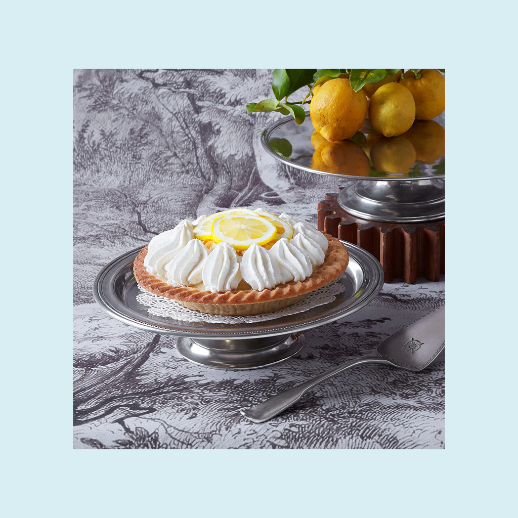 A cake stand with a lemon meringue pie on it