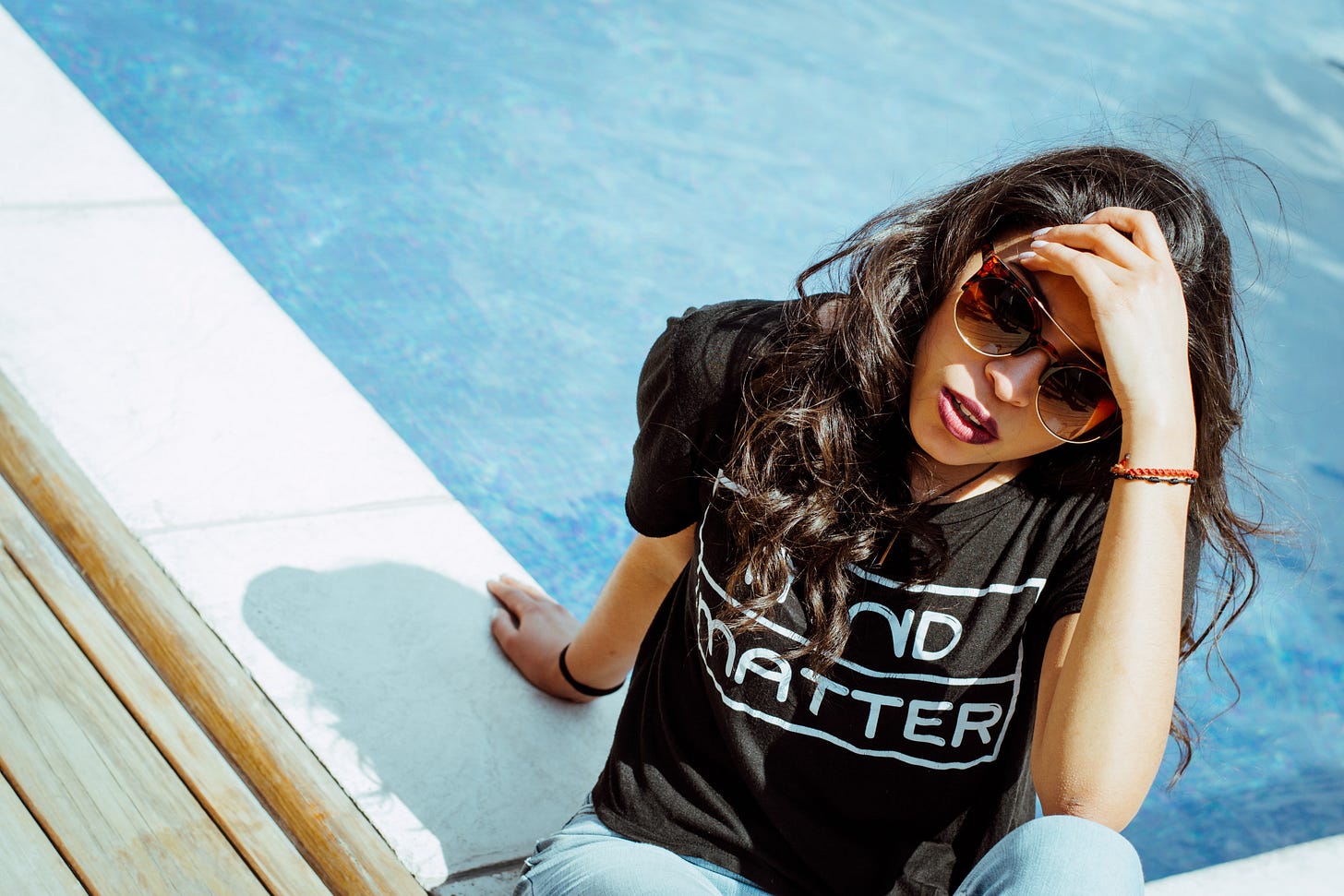 Lady clothed sitting by the edge of a swimming pool Lady clothed sitting by the edge of a swimming pool