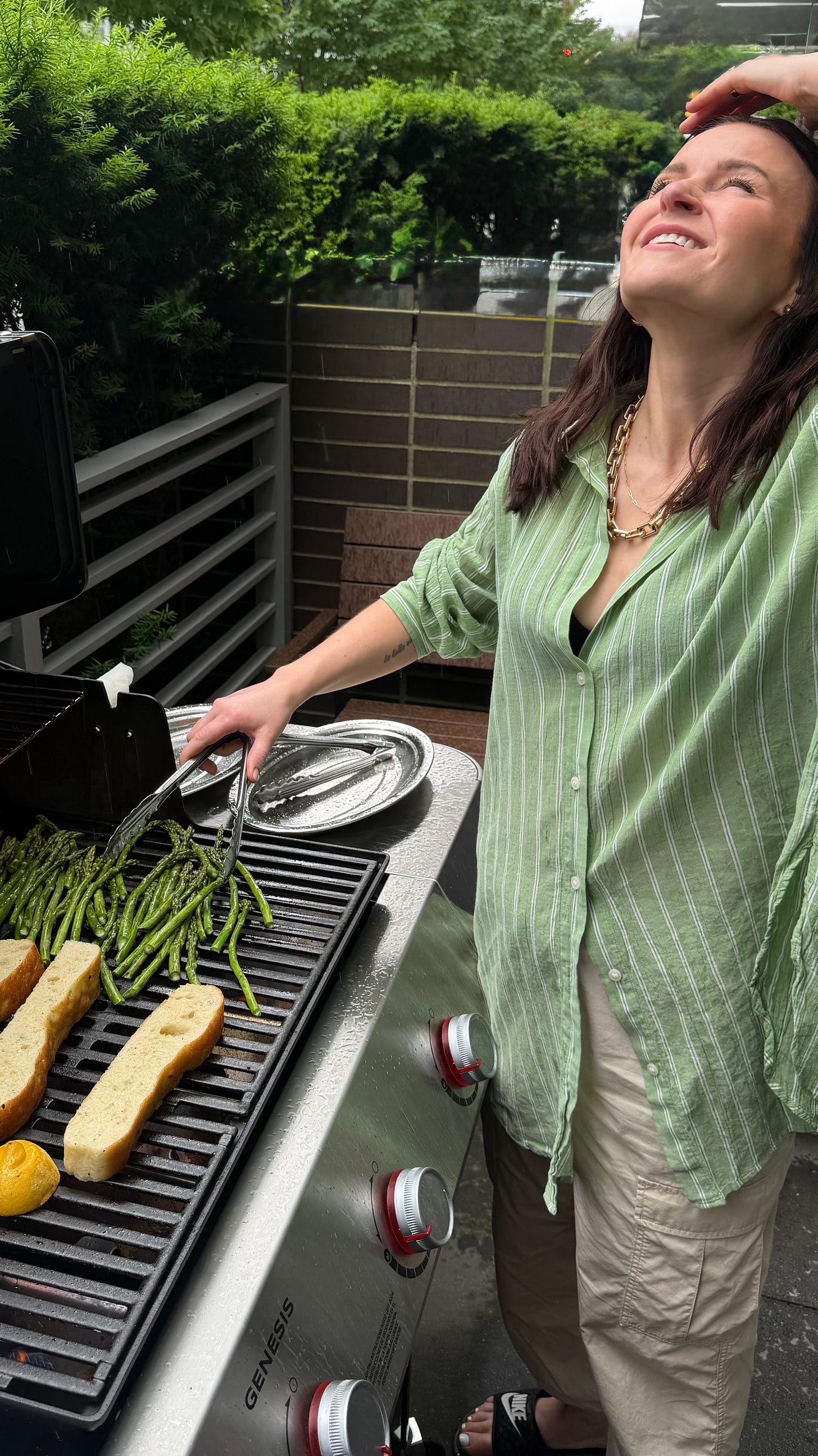 woman in a green button down shirt bbqing and getting rained on in vancouver woman in a green button down shirt bbqing and getting rained on in vancouver