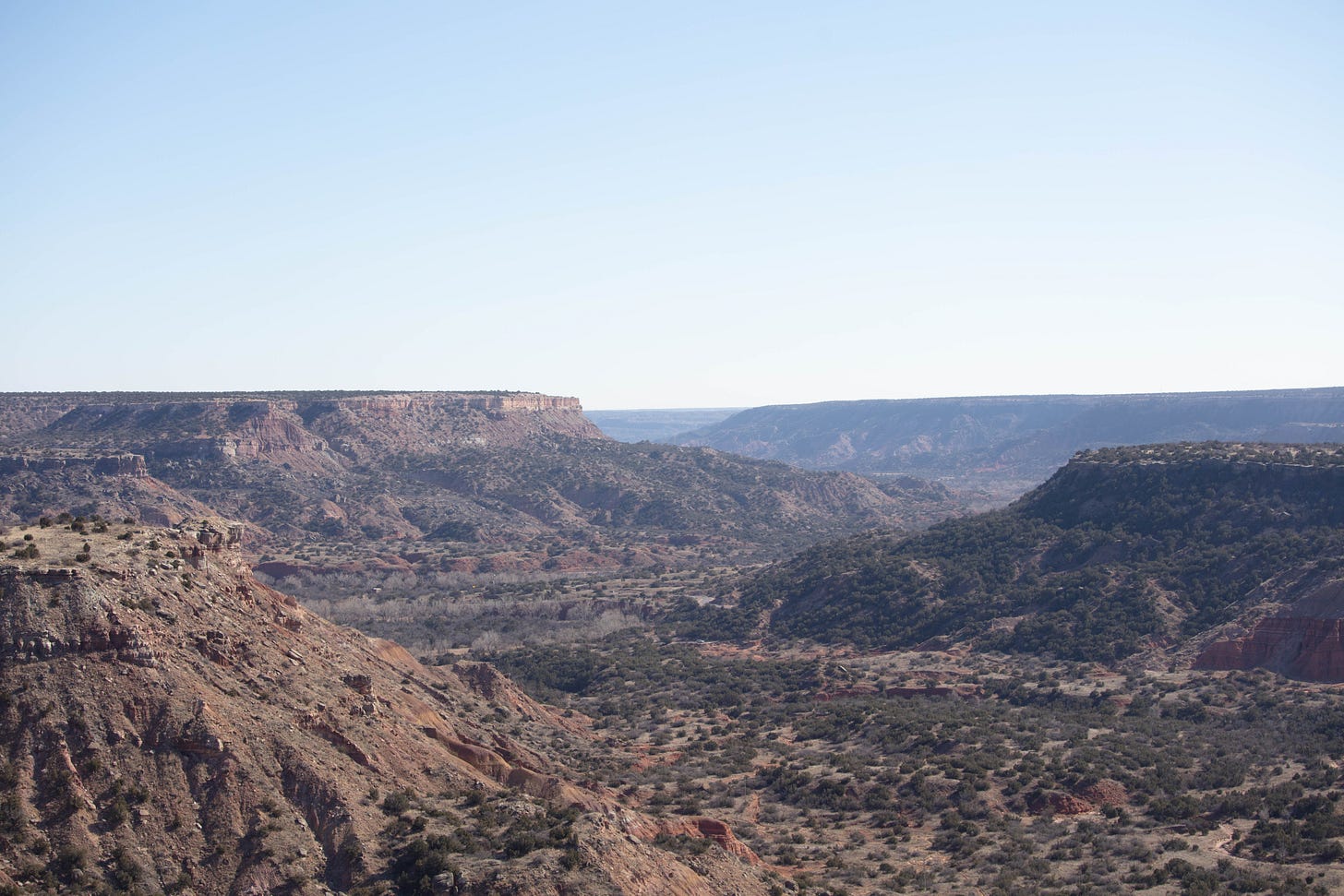 Pale blue sky over the canyon. In this view, the rocks are darker shades and more brown that in other photos.