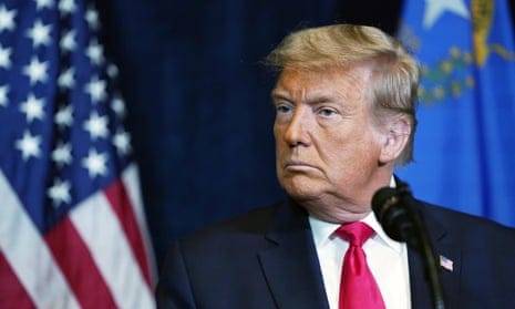 Donald Trump wearing a red tie in front of the American flag