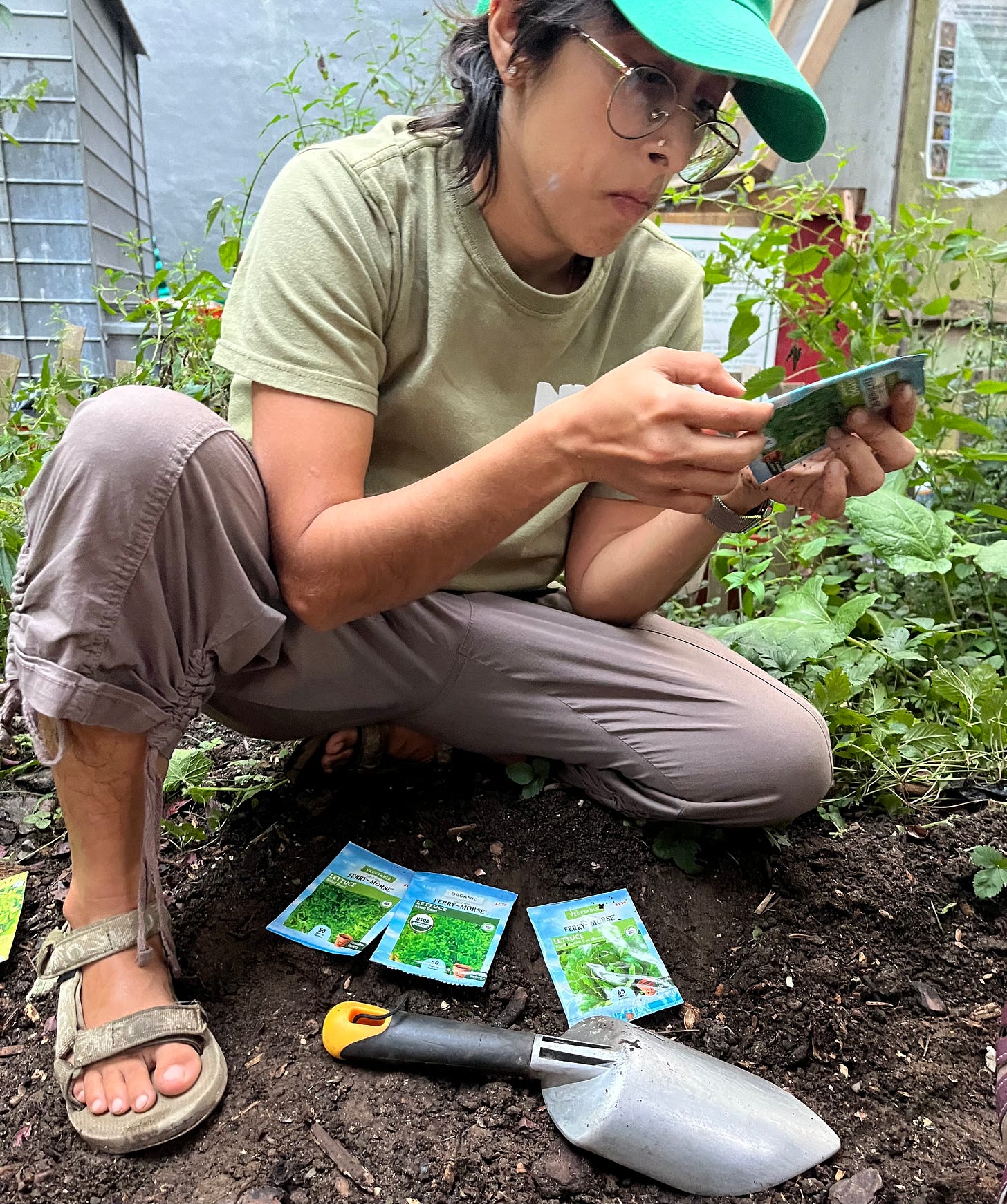 sasha crouch on dirt looking at seed packets to plant