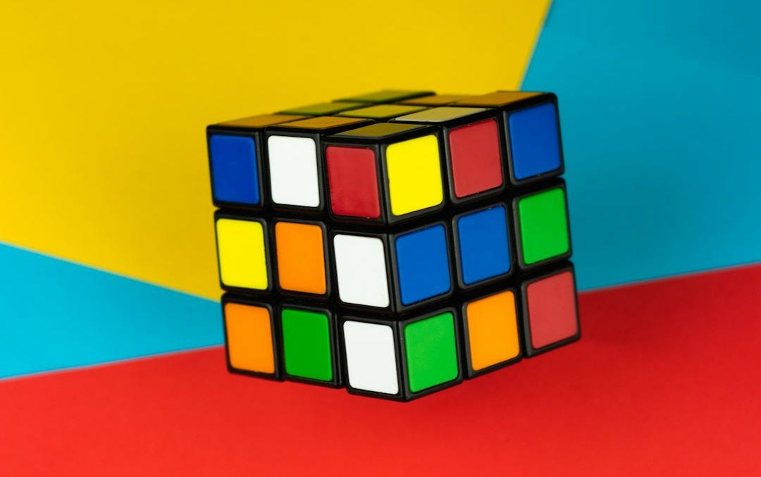 A rubik's cube rests on a colorful background.