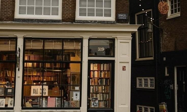 This may contain: a store front with lots of books on the windows and shelves in front of it