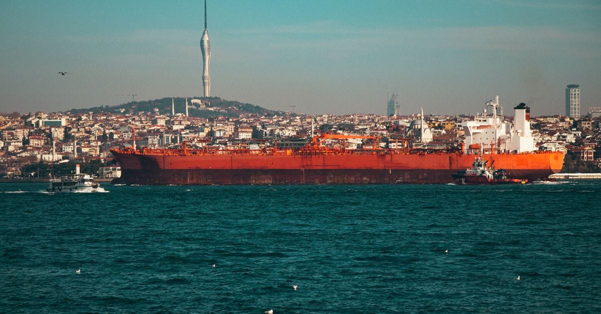 A large oil tanker navigates the Bosphorus Strait with Istanbul's skyline and Camlica Tower in the background.