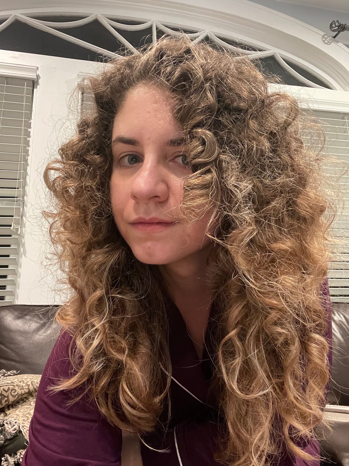 A white woman with blonde curly hair in maroon pjs