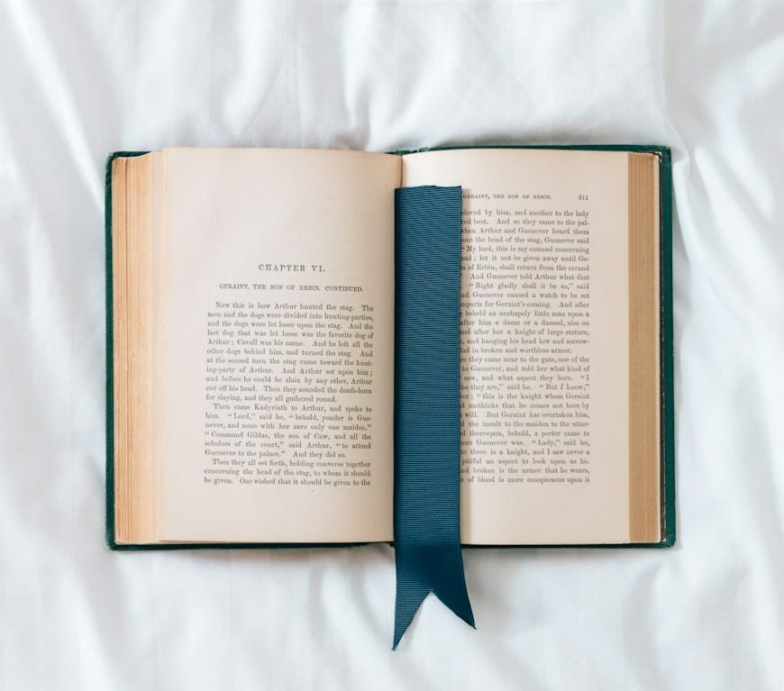an open book with a blue ribbon on a white sheet